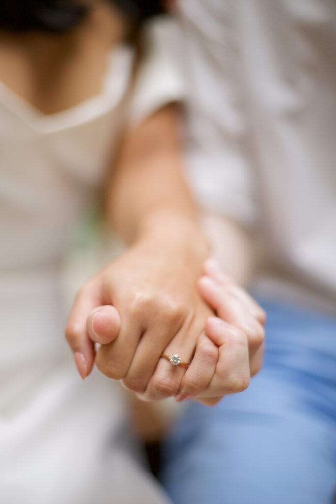 A woman and man hold hands, showing off the woman's engagement ring