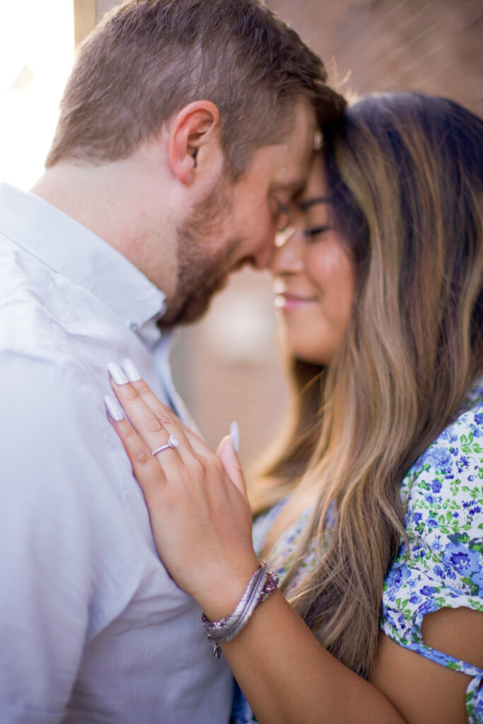 A woman places her hand on a man's chest, displaying her engagement ring