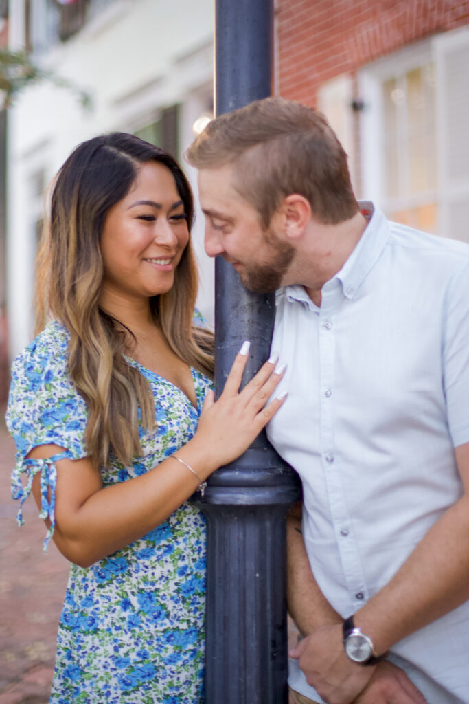 A man and a woman smile at each other around a lamppost